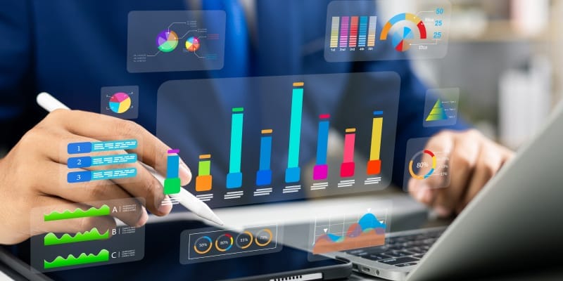 An analyst working on laptop, digital notebook with stylus and digital charts using data science technology for business.