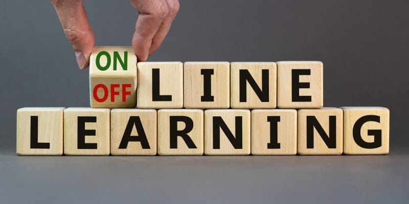 A male hand moves a cube, switching from 'offline learning' to 'online learning,' illustrating the best way to learn tech skills.